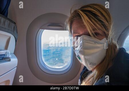 Europe - March 15th 2020: Woman on a plane with face mask for protection against the sars-cov-2 virus Stock Photo