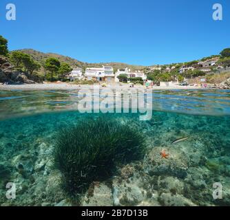 Spain Mediterranean sea summer vacations, beach coastline with buildings, split view over and under water surface, Costa Brava, Colera, Catalonia Stock Photo