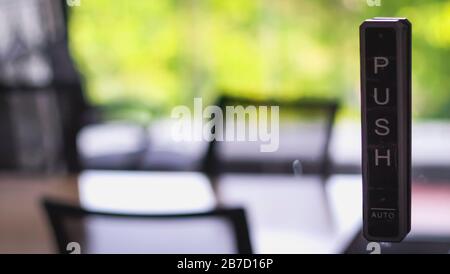 Wireless push button/press button activation switch for automatic door opening. Automatic Door Opener Wireless Push Button. Green office meeting room Stock Photo