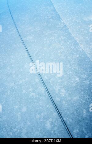 An abstract close up photograph of a crack in the frozen ice layer on a lake in Norway. Stock Photo