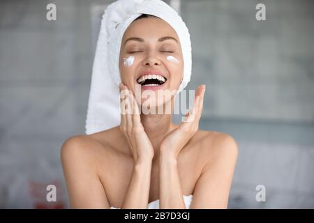 Joyful lady using professional skincare product alone in bathroom. Stock Photo