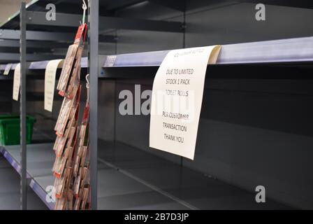 A one pack only per customer sign on a UK supermarket shelf usually filled with toilet roll now empty because of panic buying due to Coronavirus. Stock Photo