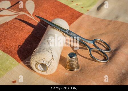 Scissors, thimble, needle and cotton thread for sewing clothes Stock Photo