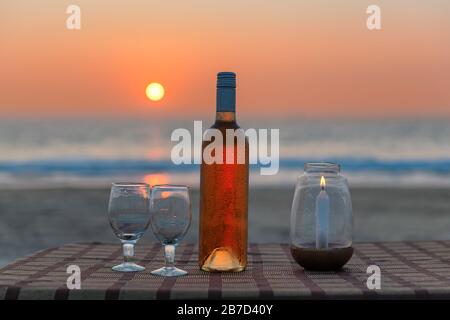 Sunset view of beach party in beach cafe with bottle of rose wine and glasses on the table , GOA, India. Stock Photo
