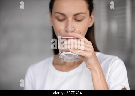 Peaceful young brunette woman drinking glass of fresh aqua Stock Photo