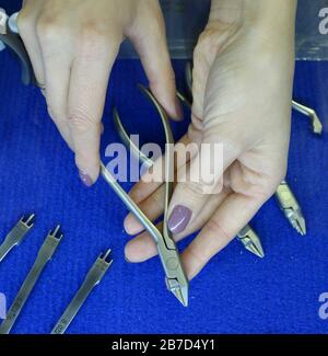 Dental surgical instruments placed on a table, woman's hands holding one of them Stock Photo