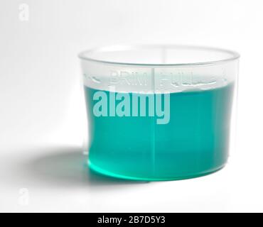 plastic liquid medicine cup against a white background. Stock Photo