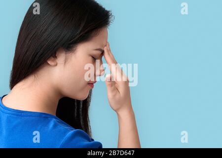 Young chinese woman standing isolated on grey background touching head having headache closed eyes frowning concerned clsoe-up copy space for text or Stock Photo