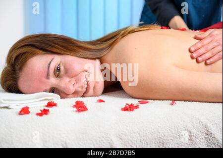 Beautiful woman getting massage and spa treatment with flower petals in spa salon . Stock Photo