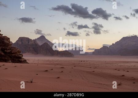 Kingdom of Jordan, Wadi Rum desert, sunset winter day scenery landscape with white puffy clouds and warm colors. Lovely travel photography. Beautiful desert could be explored on safari. Colorful image Stock Photo