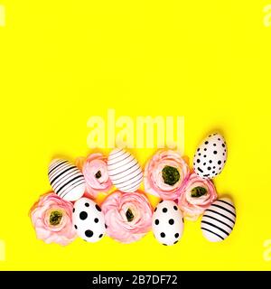 Creative graphic hand-painted eggs and ranunculus flowers on bright yellow background. Easter concept. Stock Photo