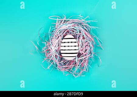 Graphic hand-painted in line egg in decorative nest on blue pastel background. Easter concept. Stock Photo