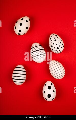 Different graphic hand-painted eggs on bright red background. Easter concept. Vertical photo. Stock Photo