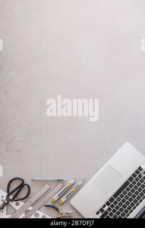 Engineering or industrial designer work place, top view with copy space. Flat lay with laptop computer, scissors, rulers and knifes with grunge backdr Stock Photo