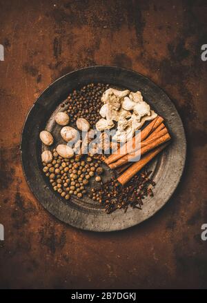Turkish traditional seven spice Yedi Bahar mix for cooking. Flat-lay of black pepper, ginger, cloves, nutmeg, cinnamon, allspice and alpinia root in b Stock Photo