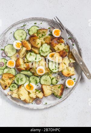 Roasted potato, cucumber and quail eggs salad, served on grey plate. Stock Photo