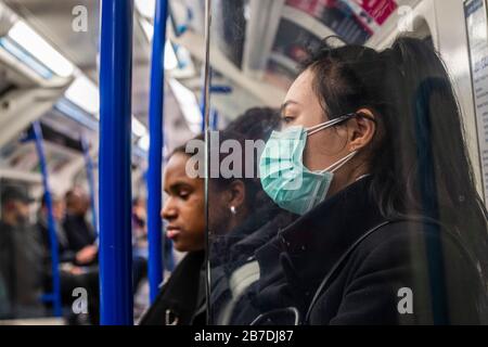 London, UK. 15th Mar, 2020. Double masking - Anti Coronavirus (Covid 19) defences, wearing inefectual masks on London Underground. Credit: Guy Bell/Alamy Live News Stock Photo