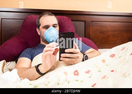 sick man laying in bed using smarthphone Stock Photo
