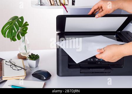 woman hands putting a sheet of paper into a copying device Stock Photo