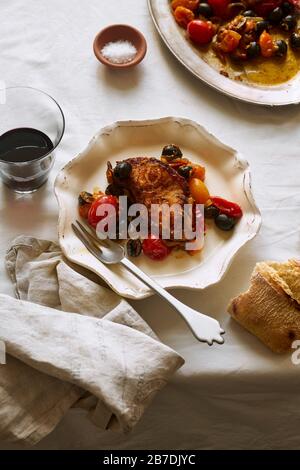 Roasted white fish with cherry tomatoes, lemon rind and olives Stock Photo