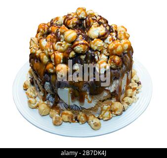 Ice cream cake with popcorn drizzled with chocolate and toffee sauce on an isolated white background with a clipping path Stock Photo