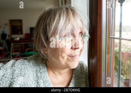 Portrait of mature woman at home looking out of window Stock Photo