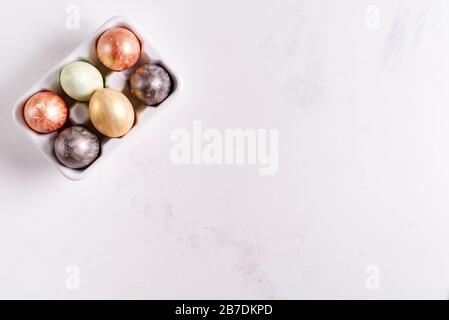 Ceramic egg tray with gold and silver painted Easter eggs on white stone background, holiday concept Stock Photo