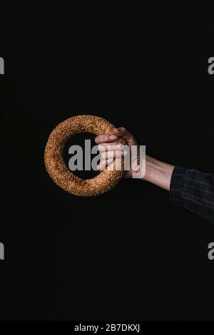 A Hand with a Bagel on a Black Background Stock Photo