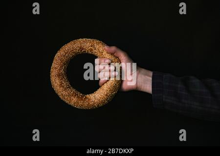 A Hand with a Bagel on a Black Background Stock Photo