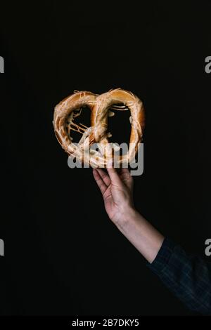 A Hand with a Pretzel on a Black Background Stock Photo
