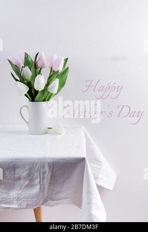 Bunch ofwhite and pink tulips in a white vase on white table with Mother's day lettering Stock Photo