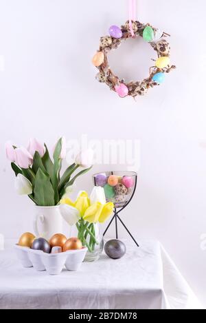 Easter table setting with tulips, easter eggs, cookies and wreath on white table Stock Photo
