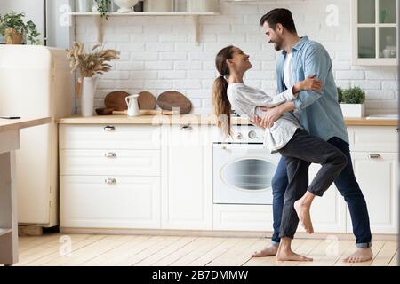 Happy loving couple dancing romantic dance on date in kitchen Stock Photo