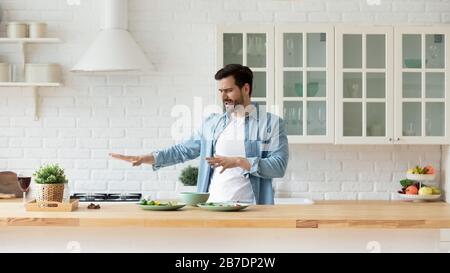 Funny young man dancing in modern kitchen, preparing food Stock Photo