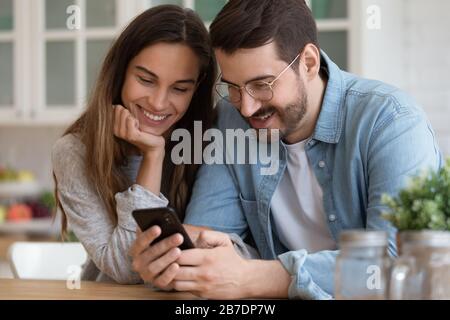 Smiling man and woman looking at smartphone screen together Stock Photo