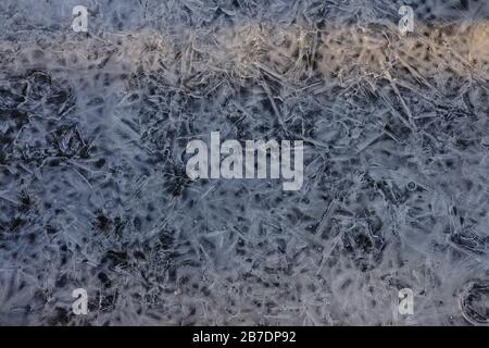 Patterns in a frozen ice puddle at the base of a tree in the local park. Ottawa, Ontario, Canada. Stock Photo