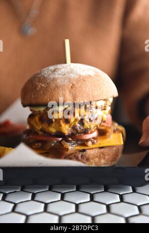 A burger on a plate, stacked in a burger bun Stock Photo