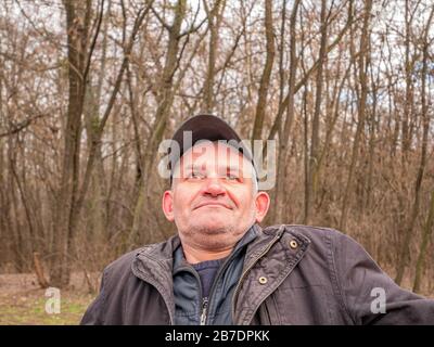 Facial expression of a mature man in a baseball cap with gray hair. Stock Photo