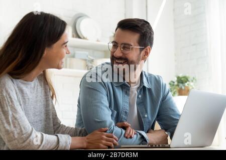 Happy loving couple using laptop together, having fun Stock Photo