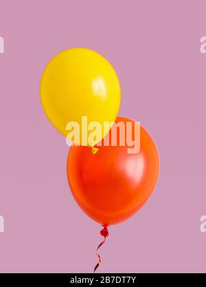Yellow and red balloons are flying over the purple background. Stock Photo