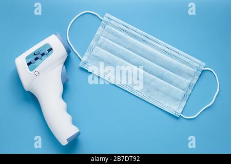 https://l450v.alamy.com/450v/2b7dt92/medical-mask-and-electronic-non-contact-thermometer-for-measuring-temperature-blue-background-2b7dt92.jpg