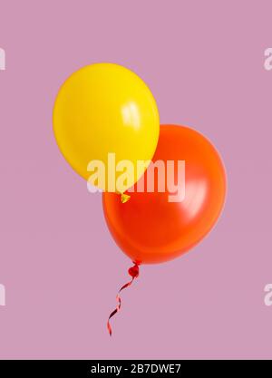 Yellow and red balloons are flying over the purple background. Stock Photo
