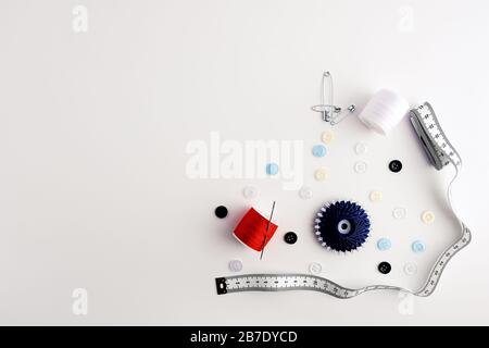 measuring tape, yarns, needles, safety pins, buttons, arranged on white background Stock Photo