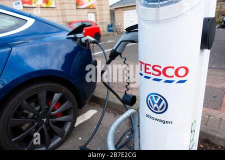 Tesla electric car charging at free charging station in Tesco supermarket, UK, United Kingdom Stock Photo