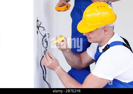 Electrician put electrical wires for wall socket using screw driver Stock Photo