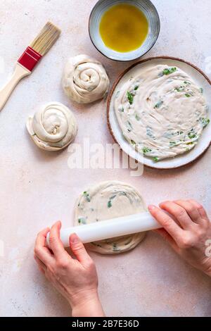 Preparing scallion pancakes.Hands rolling the dough. Stock Photo