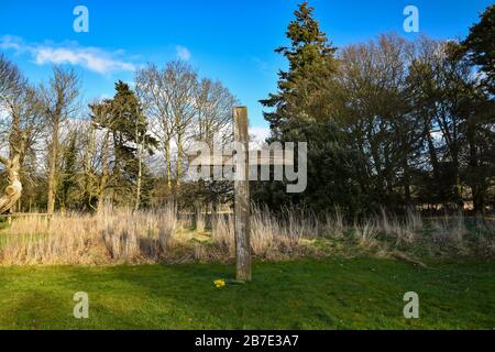 Wooden Christian cross in grounds of Balmerino Abbey, Fife, Scotland, UK on a sunny spring day with blue sky and clouds Stock Photo