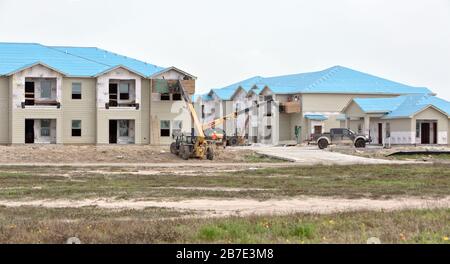 Rebuilding Salt Grass Landing Apartments. Workers installing window trim,  elevated with Caterpillar material lifter. Stock Photo