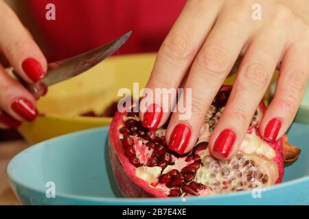 Woman with red manicure holds pomegranate. Stock Photo