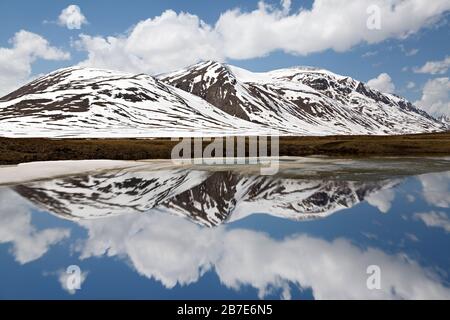 Mountain lake on top of the mountains in Barskaun, with reflections in water in Kyrgyzstan Stock Photo